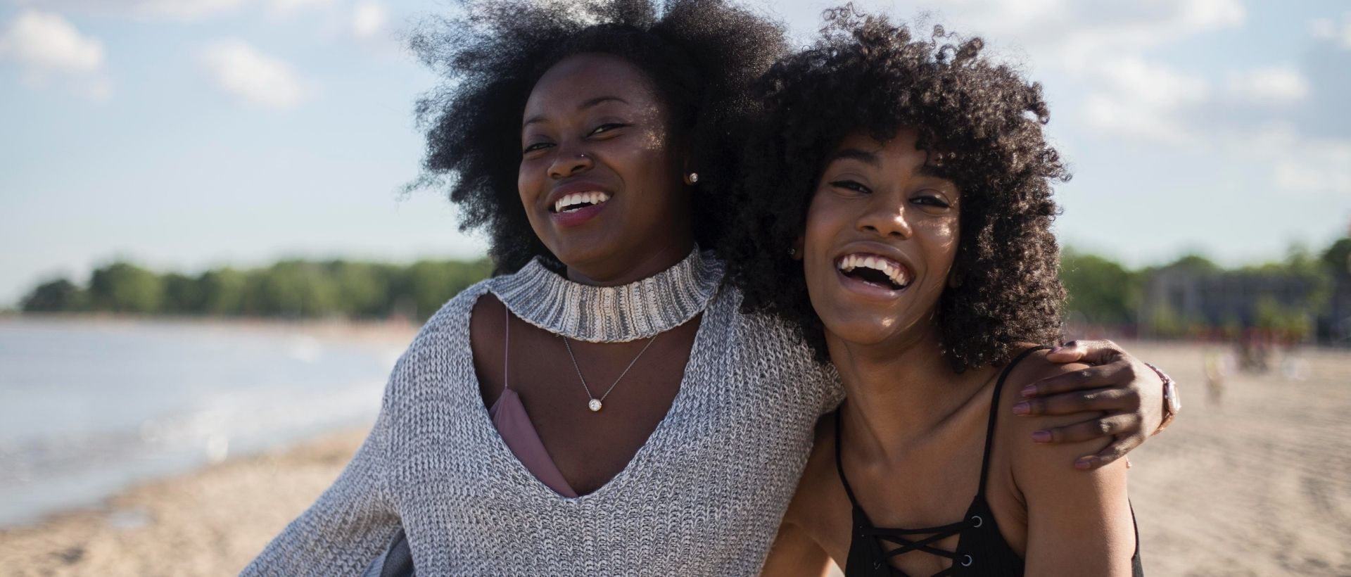 a couple of women standing next to each other on a beach.