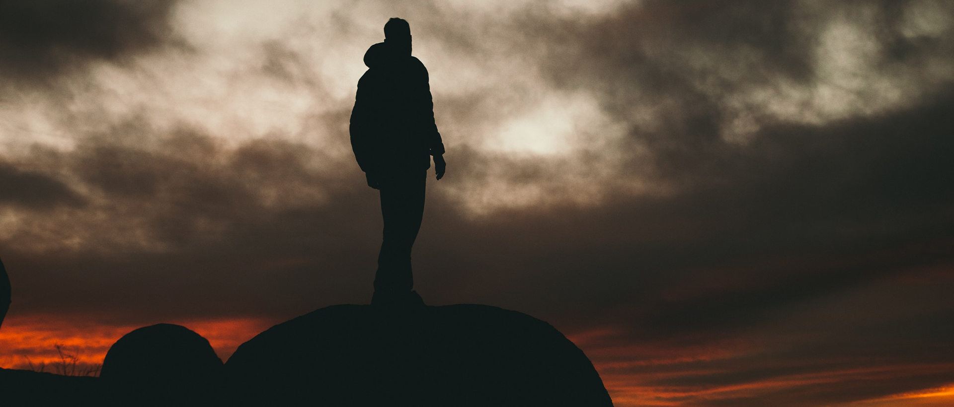 a silhouette of a person standing on top of a rock.