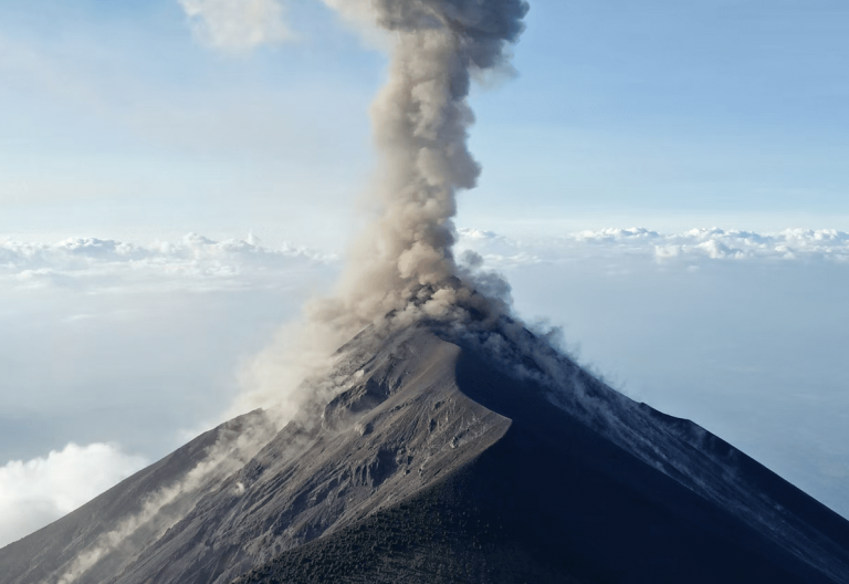 a plume of smoke billows from the top of a mountain.